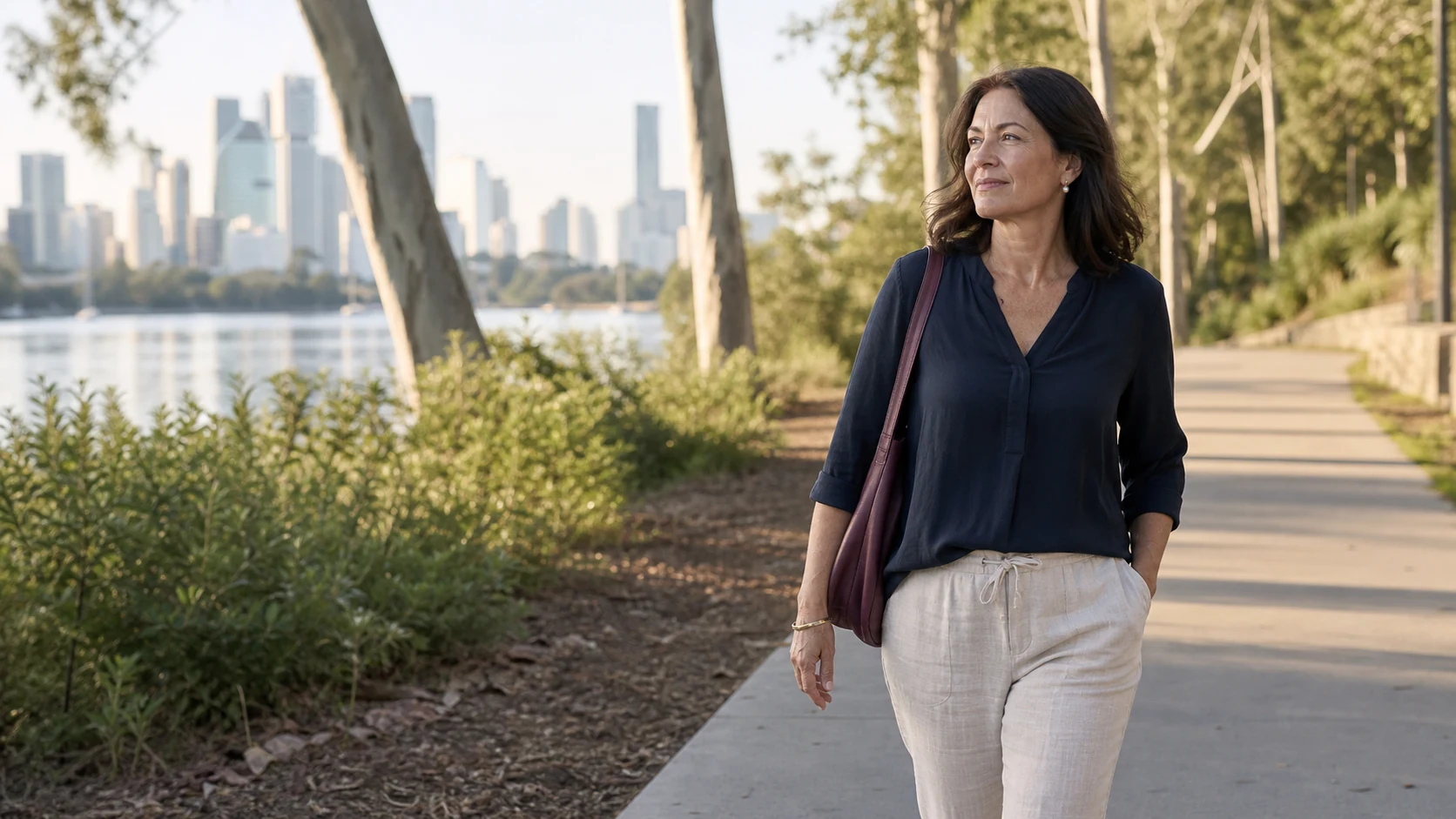 A midlife woman walking beside the Brisbane River in morning light